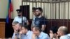 In this photo taken on June 16, 2019, Abdulmumin Gadzhiev, the religious affairs editor of the independent weekly Chernovik, stands in a cage in a court room in Makhachkala, the Caspian Sea province of Dagestan, Russia.