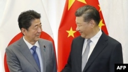 日本首相安倍晉三和中國國家主席習近平（右）在俄羅斯舉行的東方經濟論壇上握手。 （2018年9月12日）