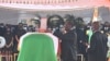 Le président ivoirien Alassane Ouattara (C) place une décoration sur le cercueil de feu le Premier ministre ivoirien Hamed Bakayoko lors de sa cérémonie d'hommage officielle le 17 mars 2021.