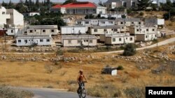 A young Jewish settler rides a bicycle in front of the West Bank settlement of Susiya, June 24, 2012.