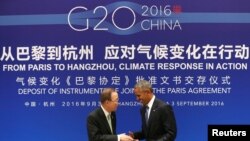 Le président américain Barack Obama, à droite, se serre la main avec le secrétaire général de l'ONU Ban Ki-moon lors d'une cérémonie de ratification conjointe de l'accord sur le changement climatique de Paris avant le sommet du G20 au Guest House de l'Etat, le 3 septembre 2016.