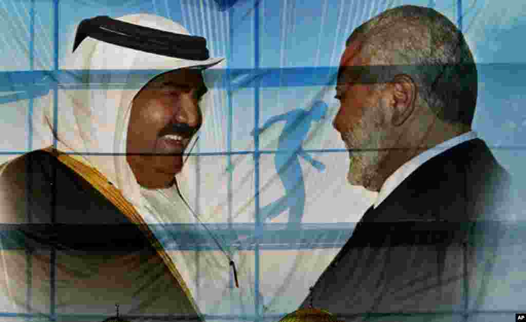 A Palestinian worker walks behind posters of the Emir of Qatar Sheikh Hamad bin Khalifa al-Thani, left, and Gaza&#39;s Hamas Prime Minister Ismail Haniyeh, right, in preparation for the upcoming visit to Gaza at Palestine Monday, Oct. 22, 2012. 