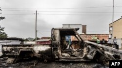 Wakazi wakipita karibu ya gari lilichomwa katika mapigano makali katika mitaa ya Goma, Januari 28, 2025. Picha ya AFP