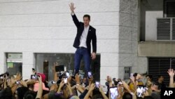 FILE - Opposition leader Juan Guaido waves to supporters during a rally at Bolivar Plaza in Chacao, Venezuela, Feb. 11, 2020. Guaido returned home from a tour of nations that back his effort to oust socialist leader Nicolas Maduro.