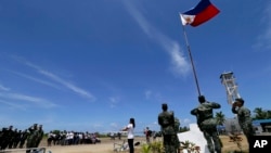 2015年5月11日，一個菲律賓居民和菲律賓軍人一起在南中國海的斯普拉特利群島（南沙群島中的派格阿薩島（中業島）舉行升旗儀式。（資料照片）