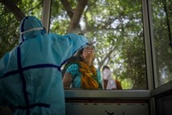 A woman gets a nasal swab taken to test for the coronavirus in Noida, outskirts of New Delhi, India, July 16, 2020.