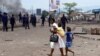 ARCHIVES - Une mère et ses enfants passent près de la police anti-émeute lors d'une manifestation à Kinshasa, en République démocratique du Congo, lundi 19 septembre 2016.
