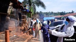 Des responsables ougandai de la santé portant un équipement de protection désinfectent le marché en plein air de Nakawa dans le cadre de mesures de prévention de la propagation du coronavirus à Kampala, le 17 avril 2020.