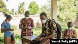 Des agents de santé manipulent leurs téléphones avant une distribution de moustiquaires à Pahou, à 30 km à l'ouest de Cotonou, au Bénin, le 28 avril 2020.