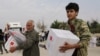 FILE - People hold boxes of aid donated by the Turkish Red Crescent in the border town of Tal Abyad, Syria, Oct. 19, 2019.