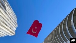 Un drapeau turc suspendu entre deux gratte-ciel flotte au vent, à Istanbul, jeudi 23 avril 2020.